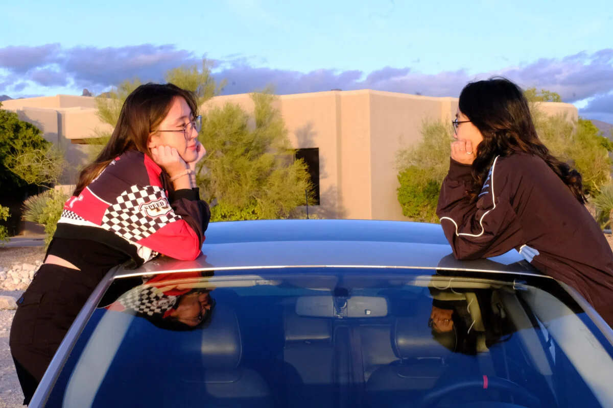 Lydia and Sophie facing each other on a car