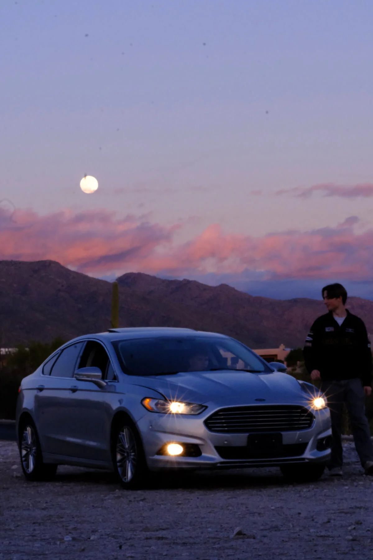 Adam next to a car in front of mountains